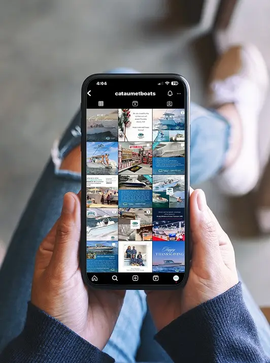 holding mobile phone viewing social media profile - cataumet boats